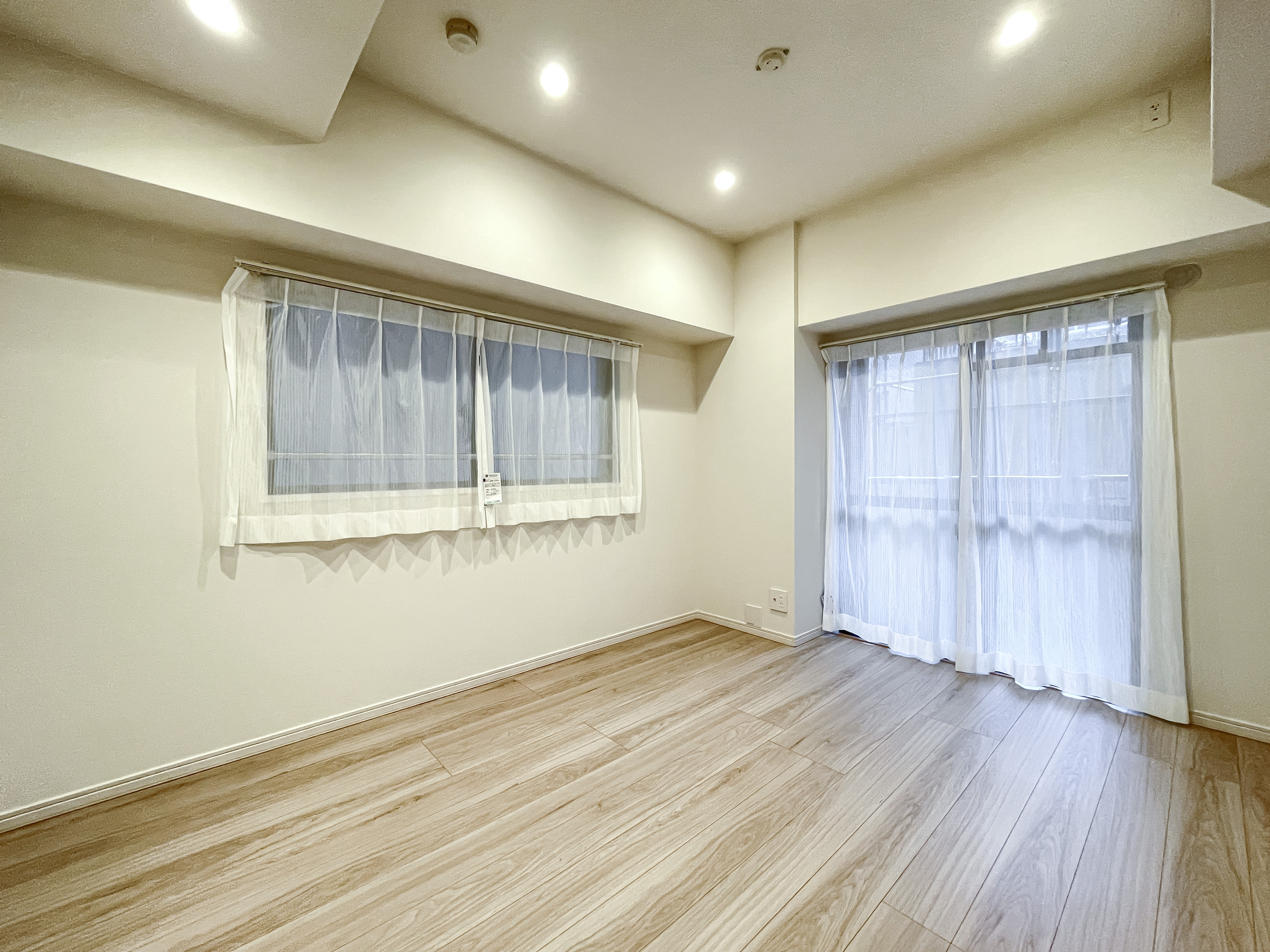 広い窓と木目調の床が特徴的な居住空間の室内写真