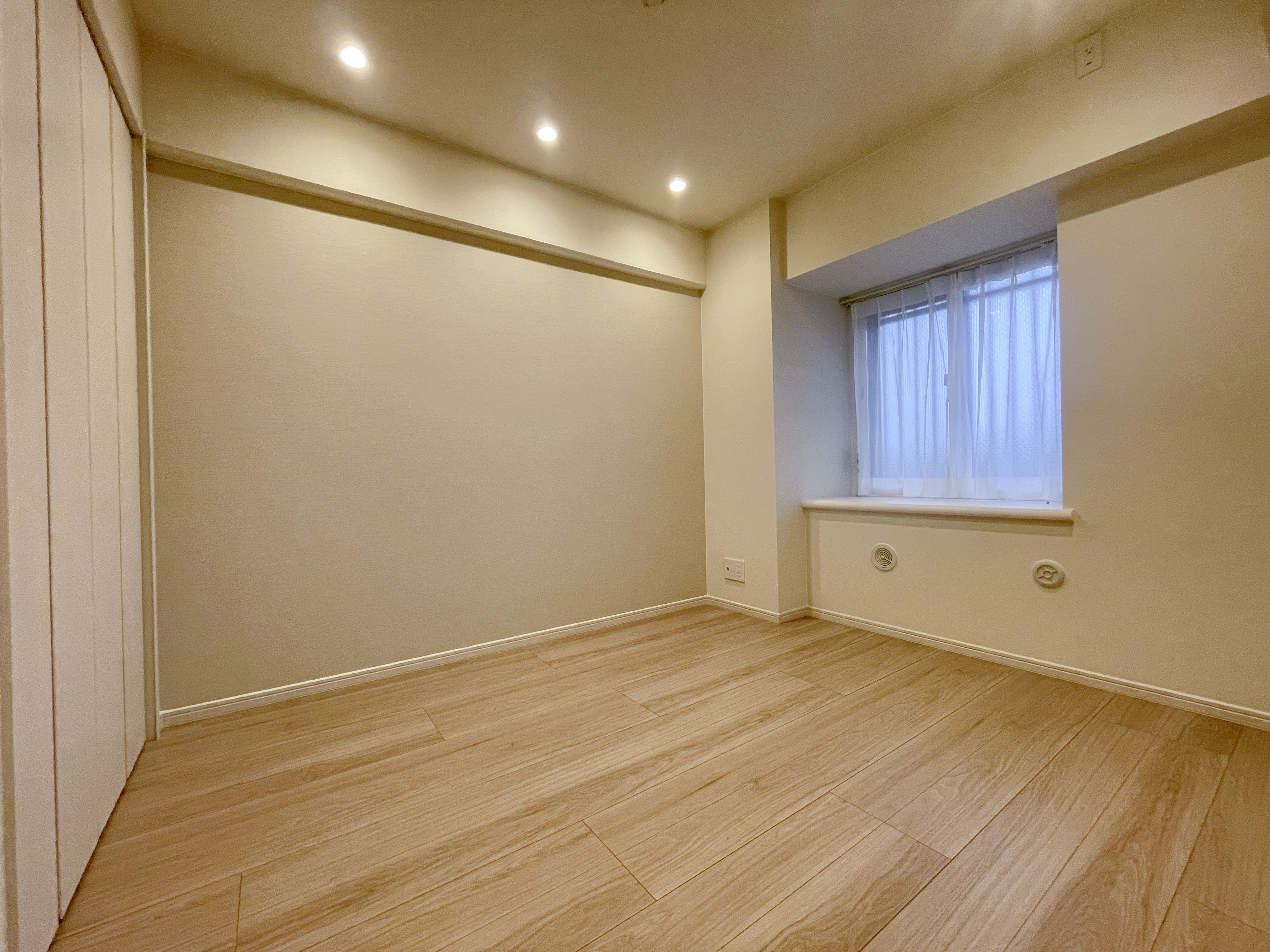 空のリビング部屋の室内写真。窓と照明が備わった広々した空間を撮影したため、リビング・LDKに該当します。