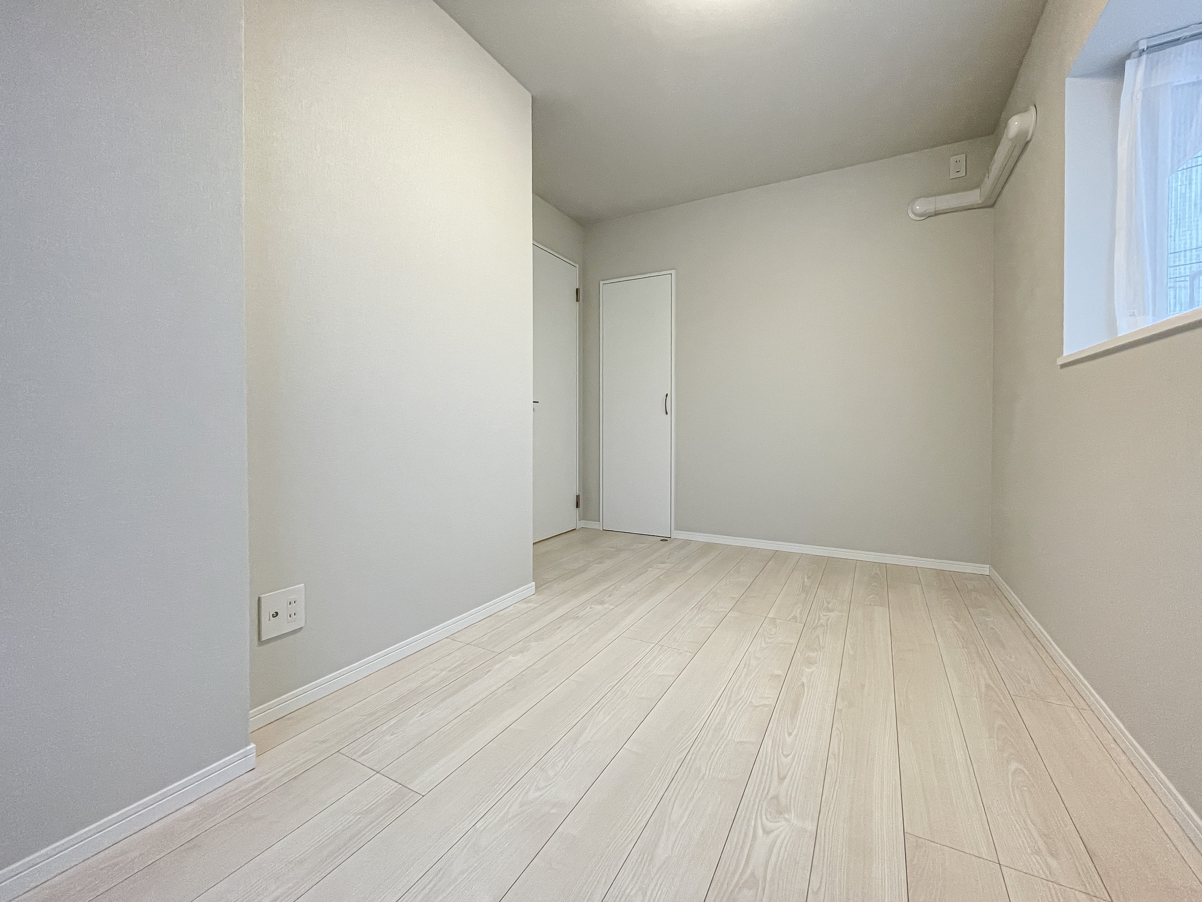 空の部屋でドアと窓が確認できる個室の室内写真