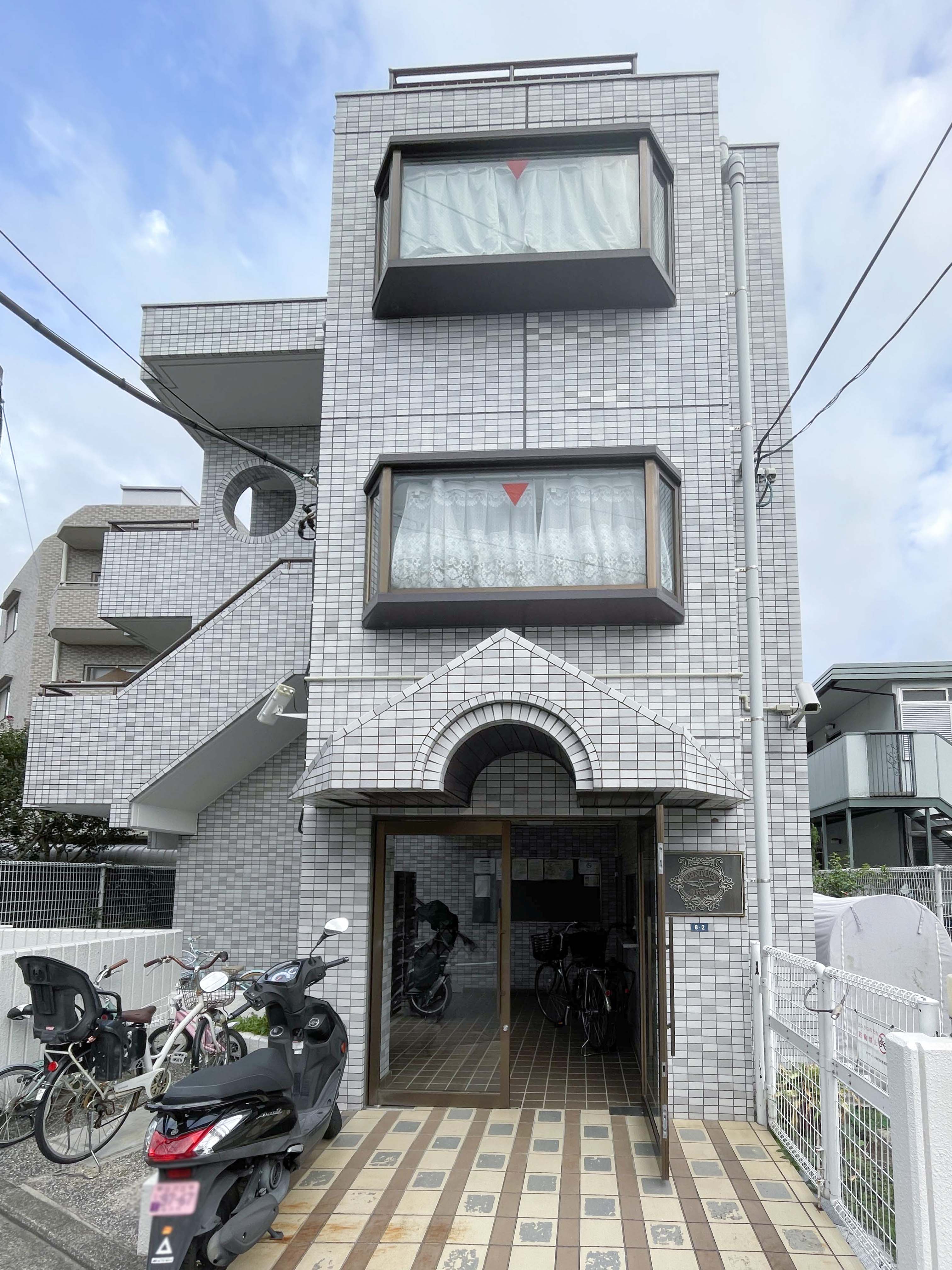 建物の外観全体が写り、窓や玄関、周囲の駐車スペースを含む全体像