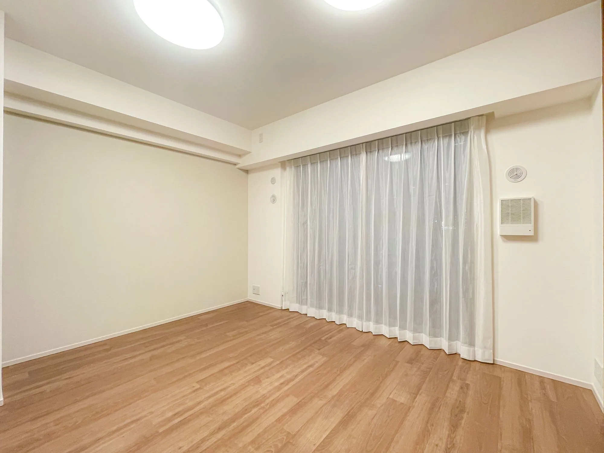 窓と天井照明が特徴の広々とした室内空間を撮影した写真