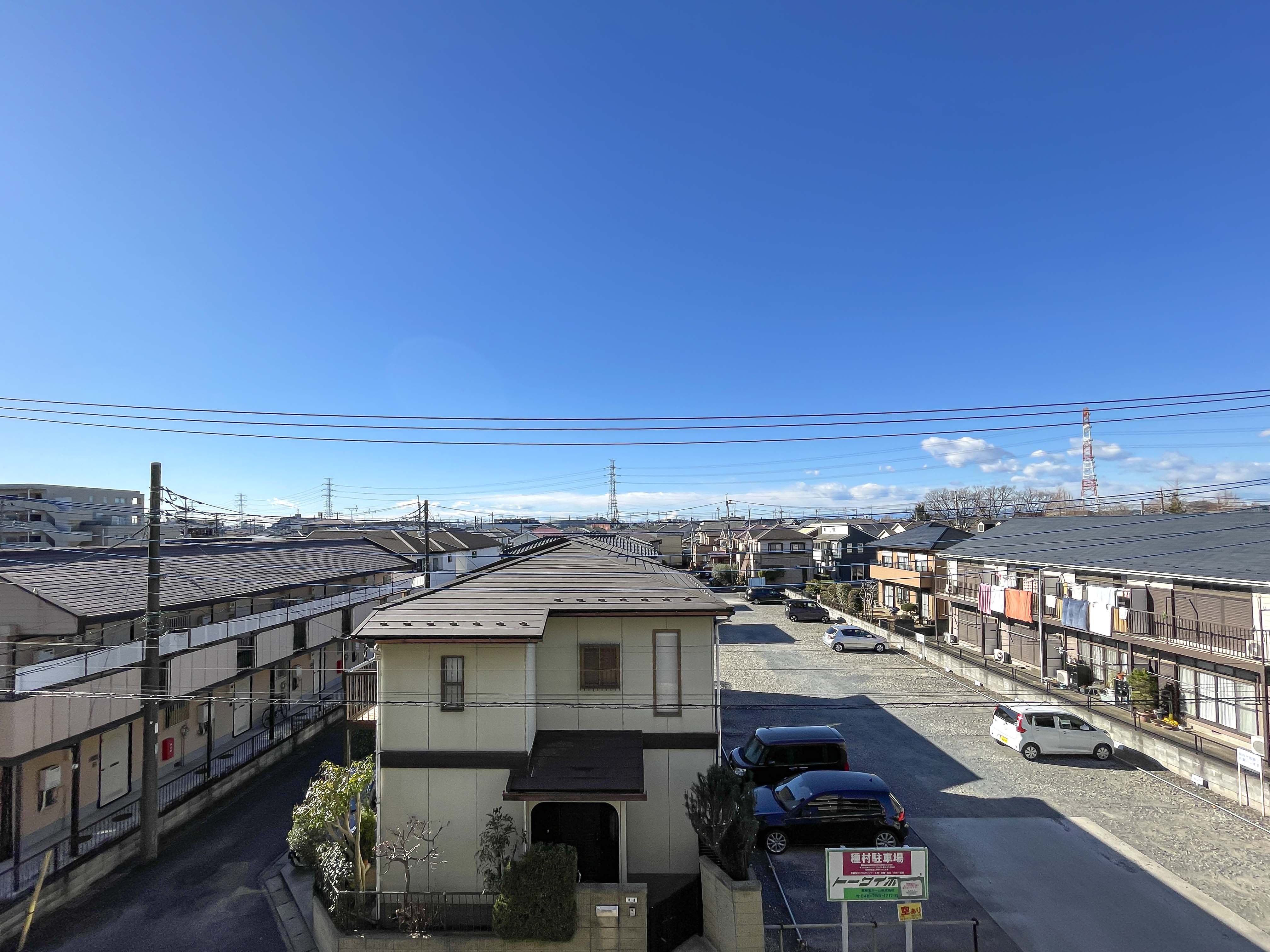 住宅街の道路や駐車場など周辺施設を含む広範囲の外観写真