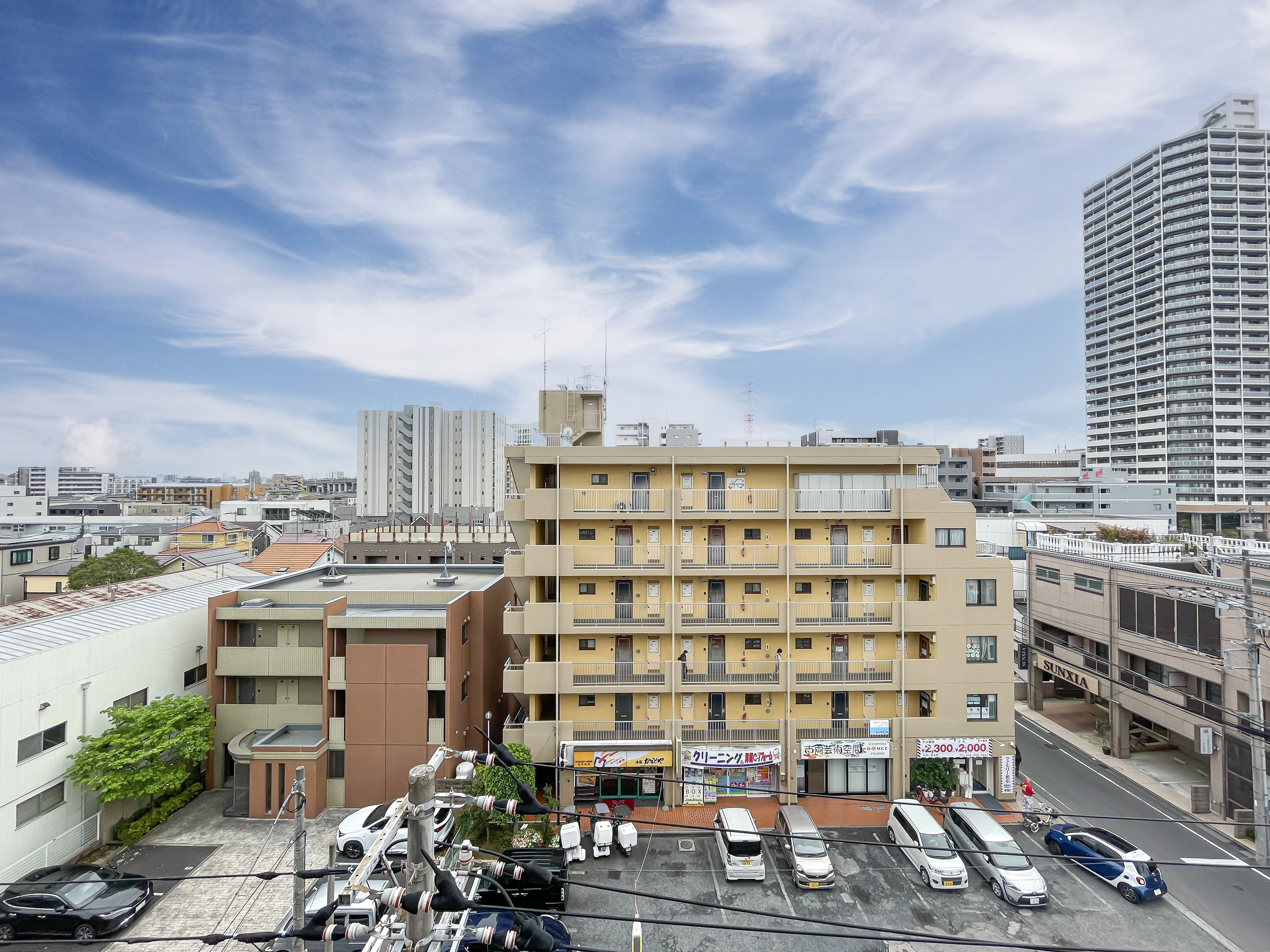 建物の外観が中心に写り、周辺の道路や駐車場も含む全体的な景観