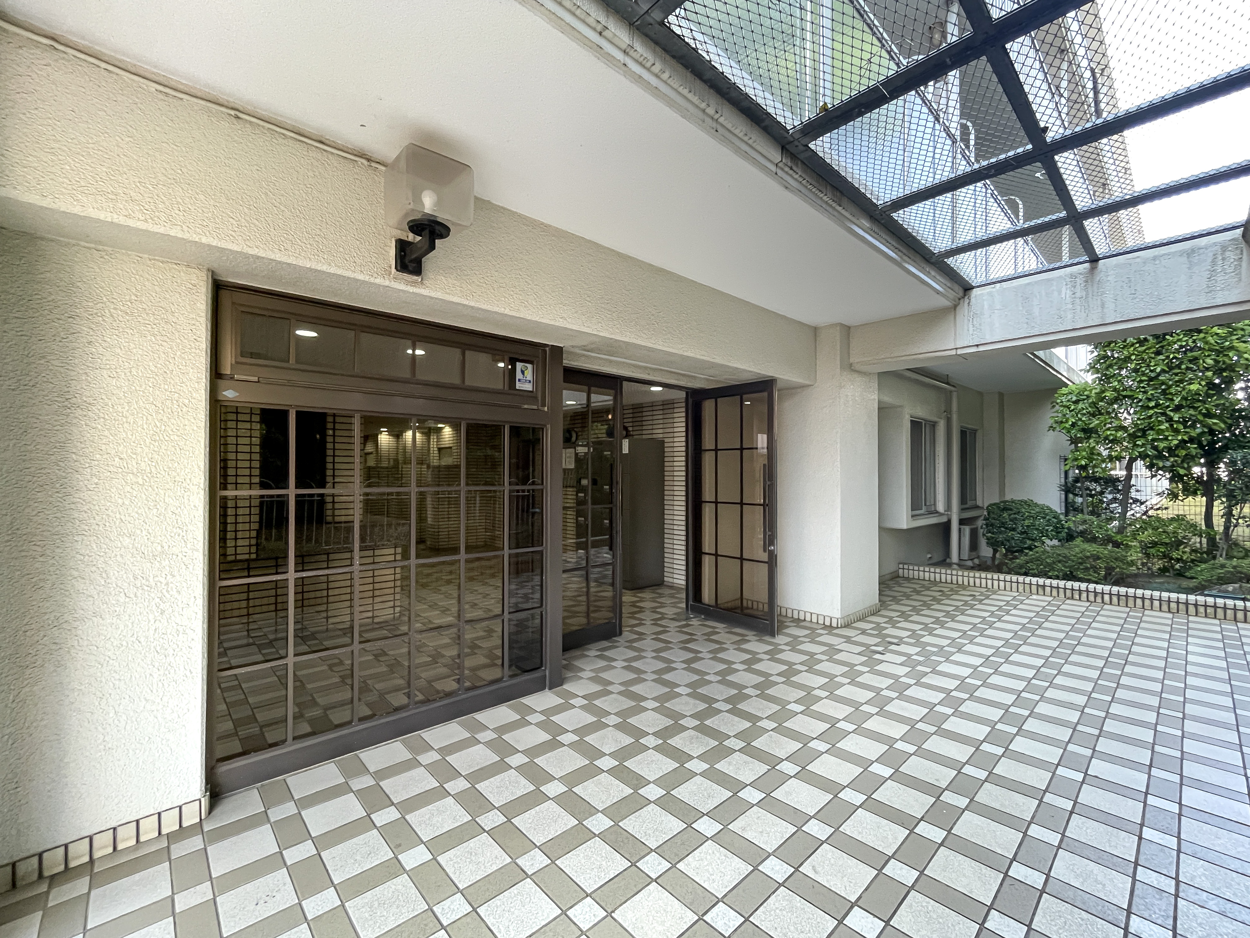 玄関のガラスドアと屋根付きの通路が主体の写真