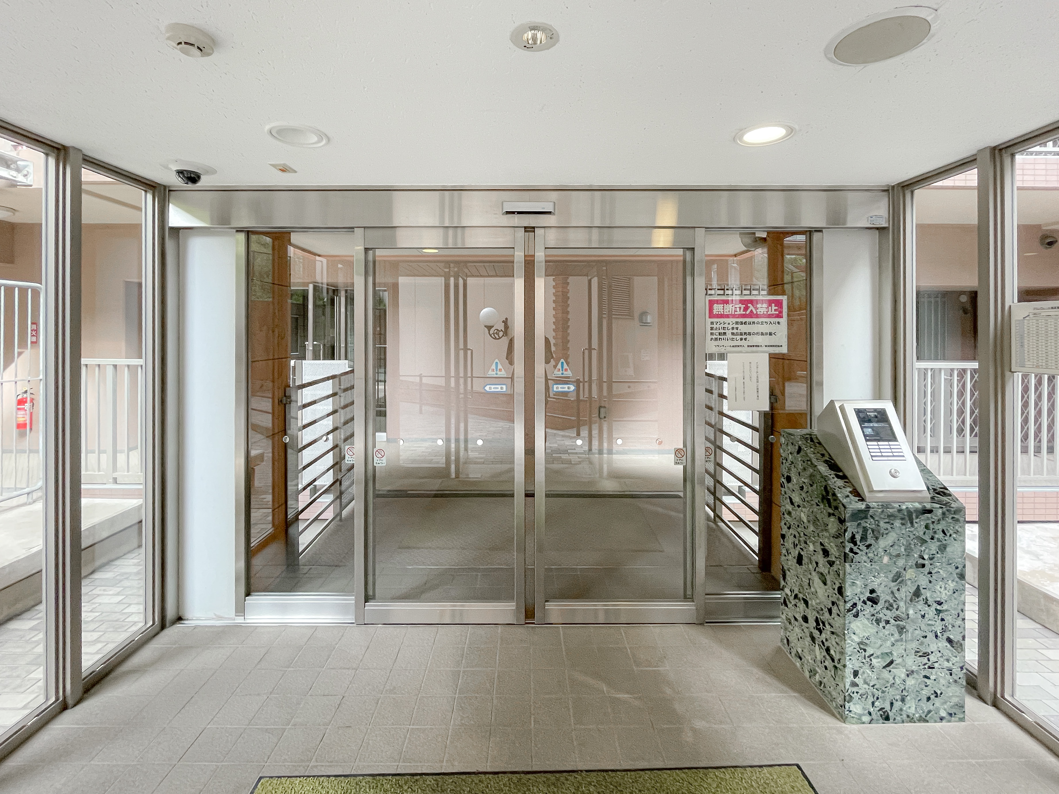 建物の玄関部分（ガラスドア、受付カウンター、掲示板）が主体の画像