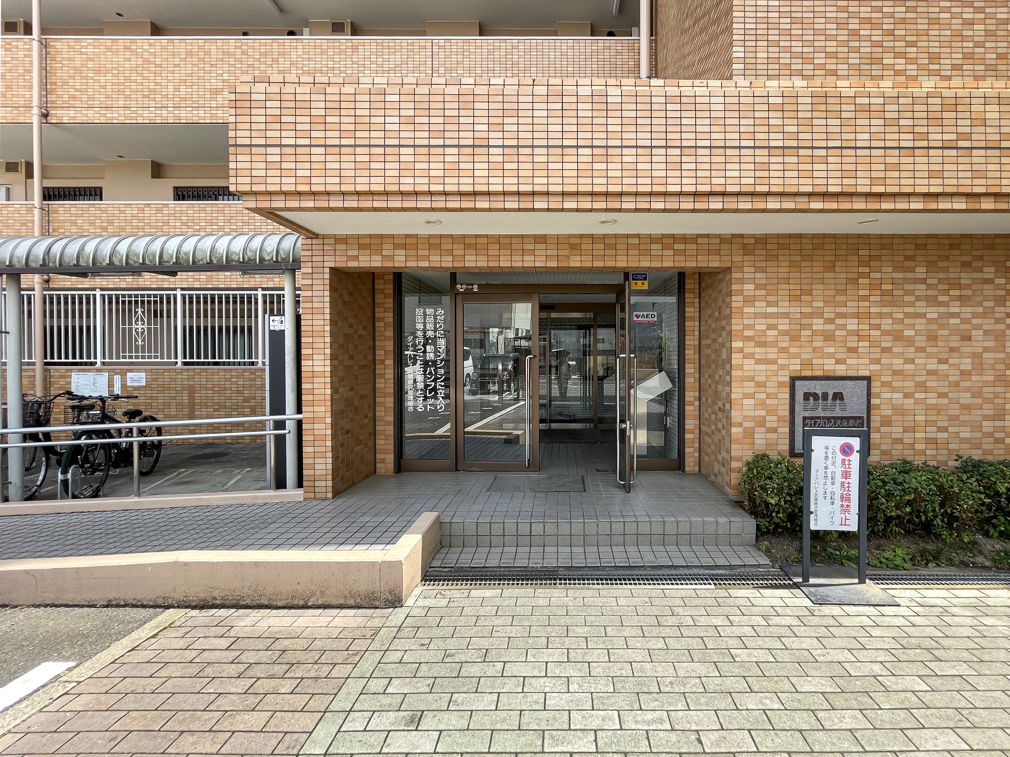 建物の玄関部分（ガラスドア、階段、周囲の看板など）が中心に写っている外観写真