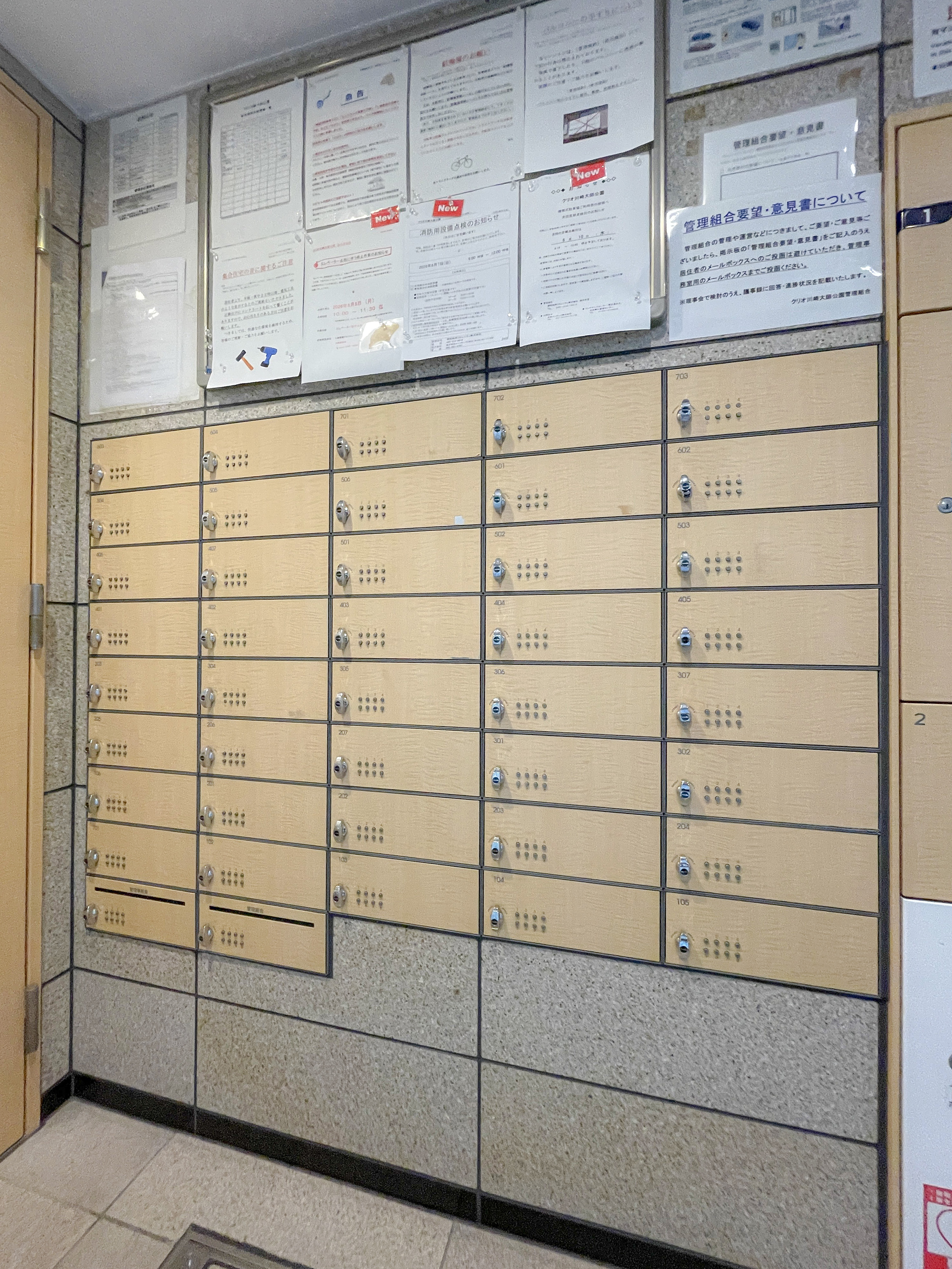 マンションの共用部の郵便受けと掲示板が写った画像