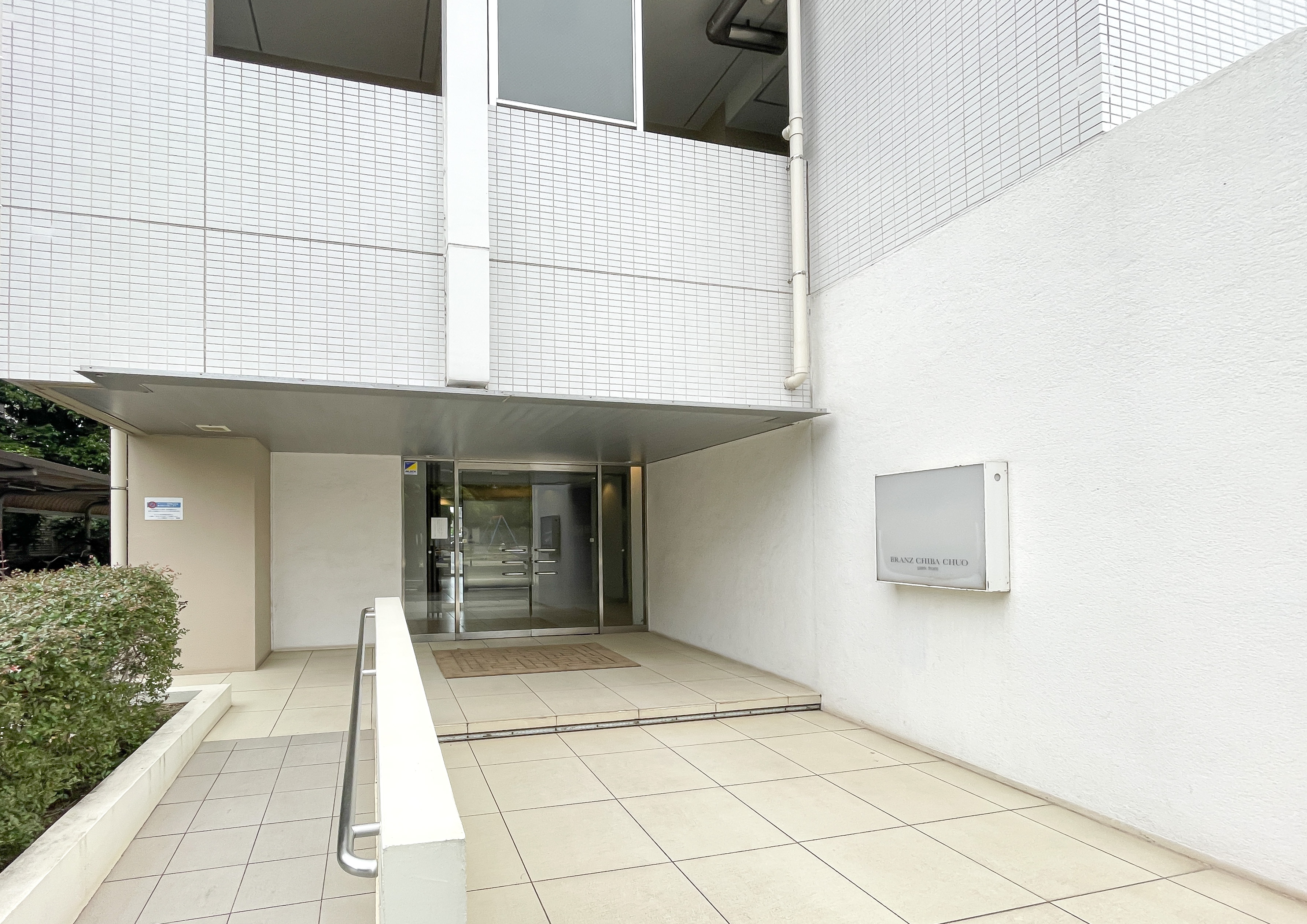 建物の外観を捉えた写真で、エントランス部分を中心とした建物の外壁や周辺環境が主体