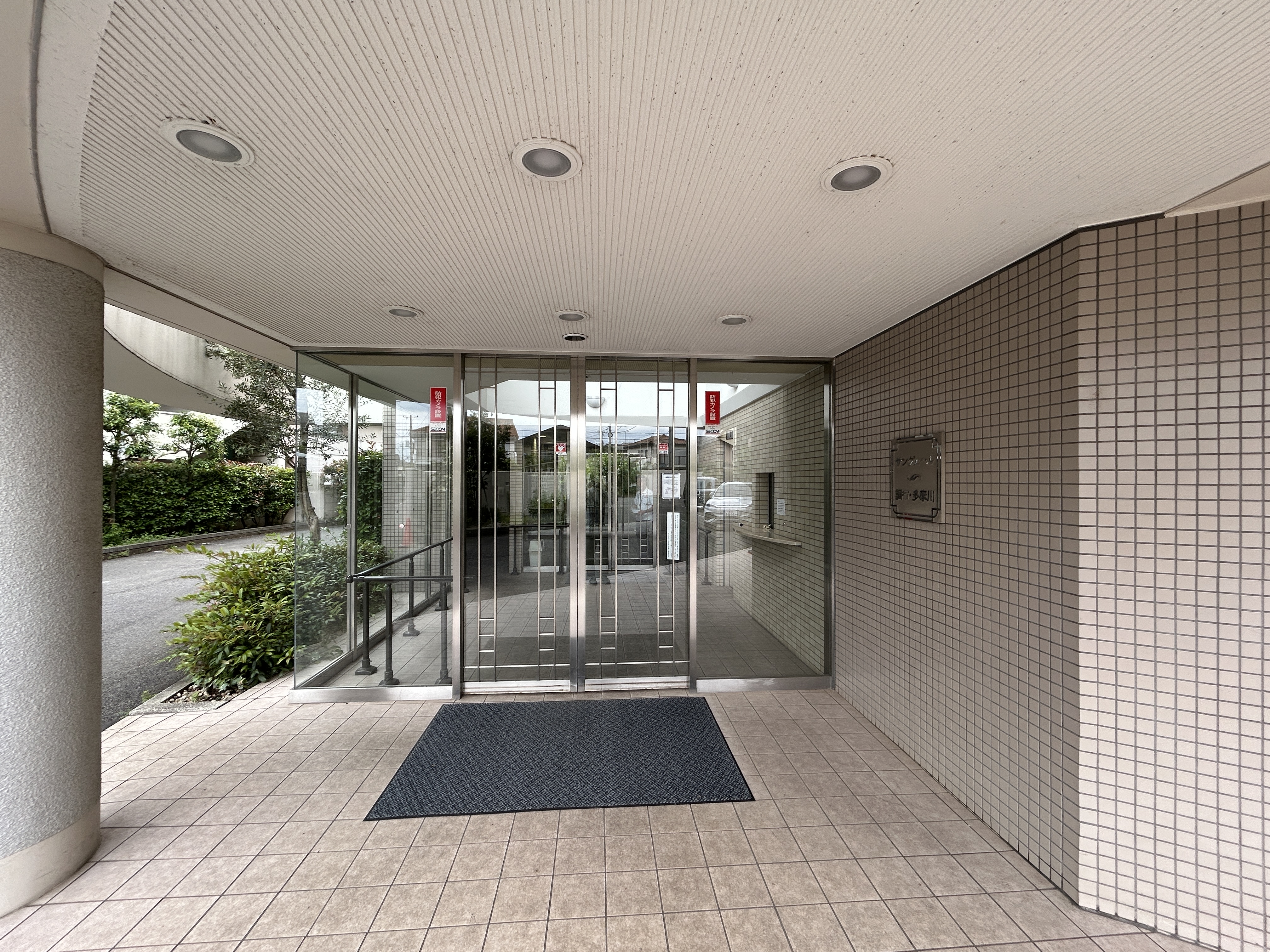 ガラスドアと玄関マットが中心の入口エリアを撮影した写真