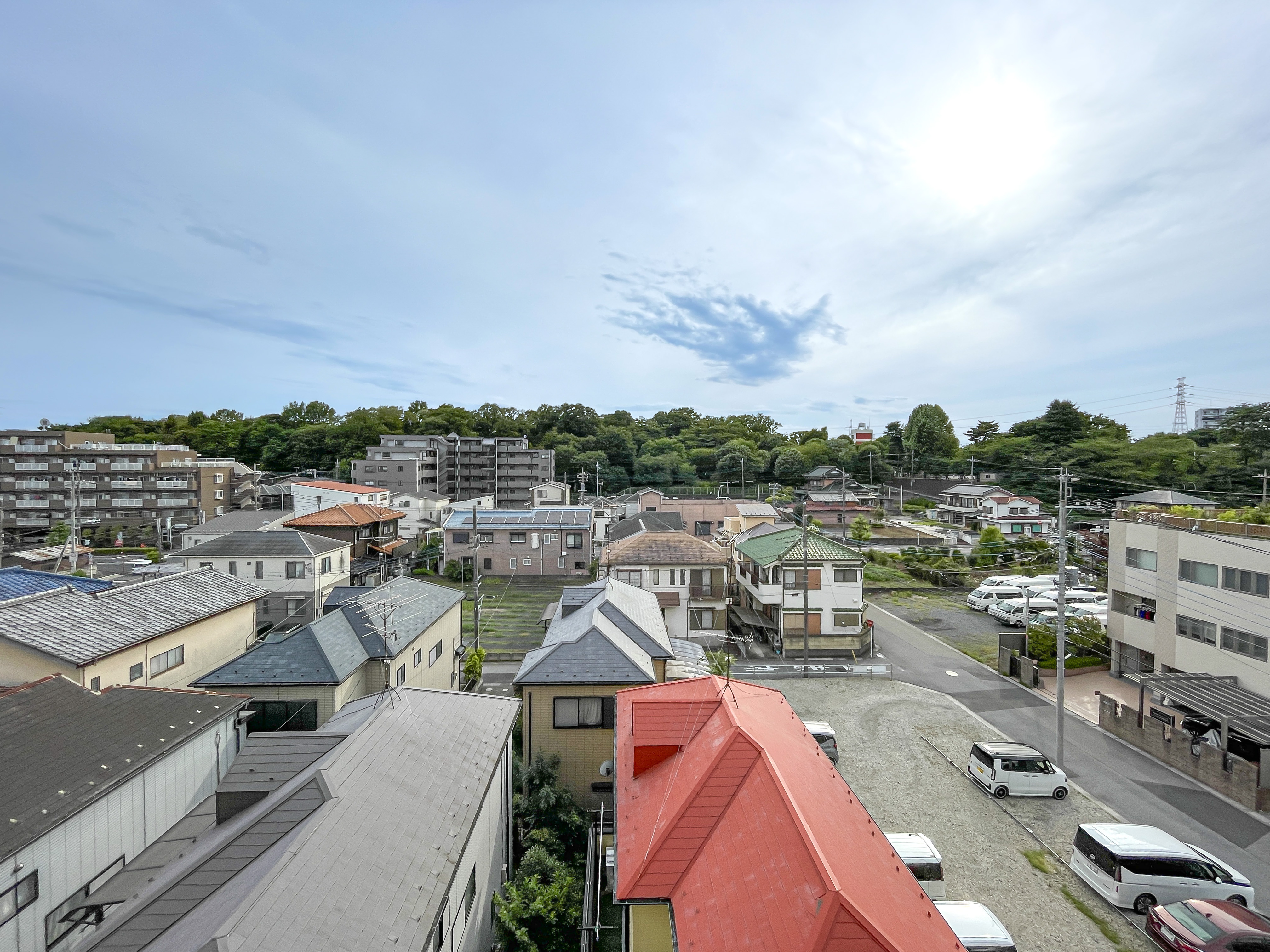 住宅街の道路、駐車場、周囲の木々を含む広域の周辺環境を捉えた画像