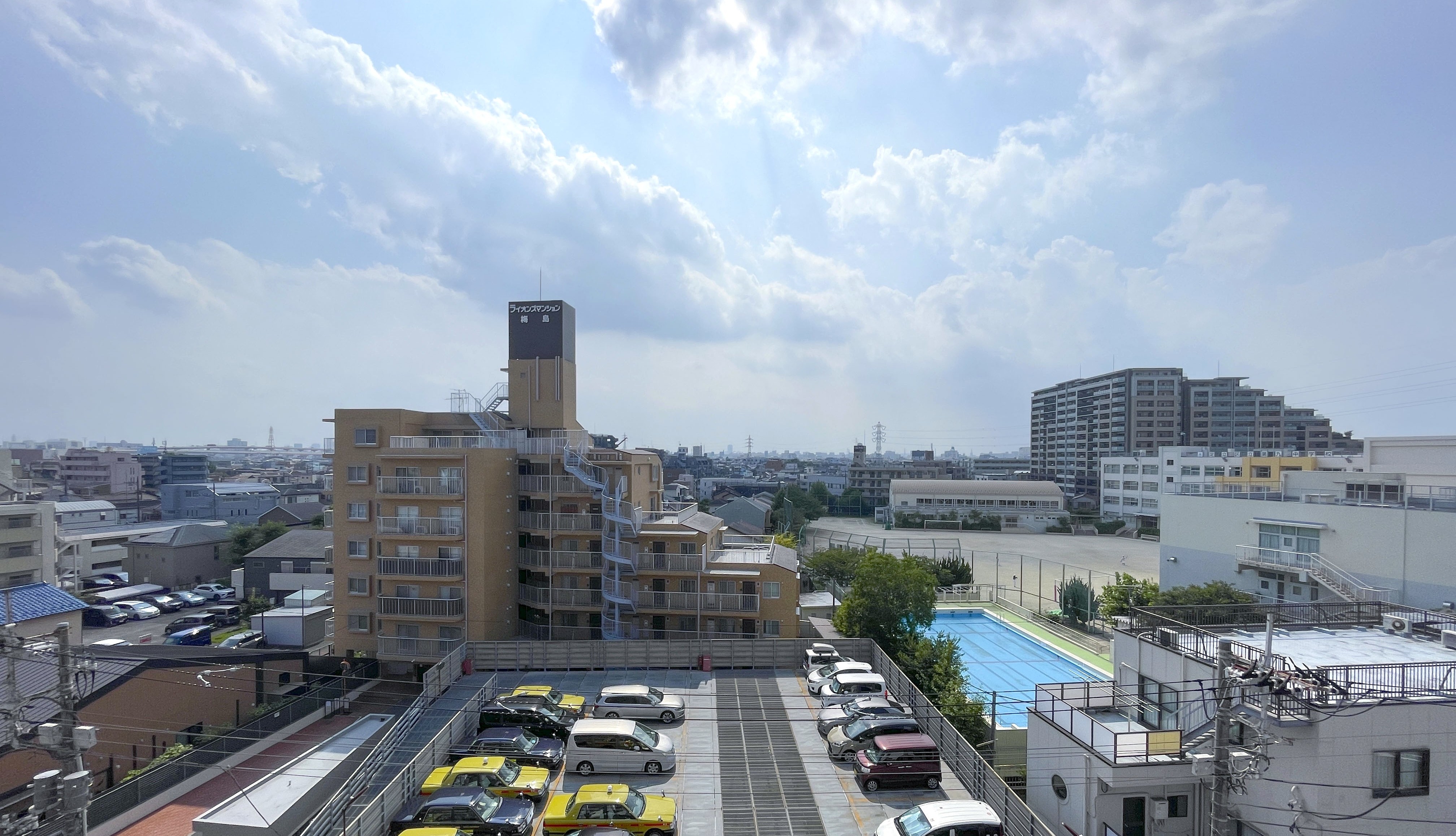 建物周辺の道路、駐車場、プールなど周囲の施設を含む景色
