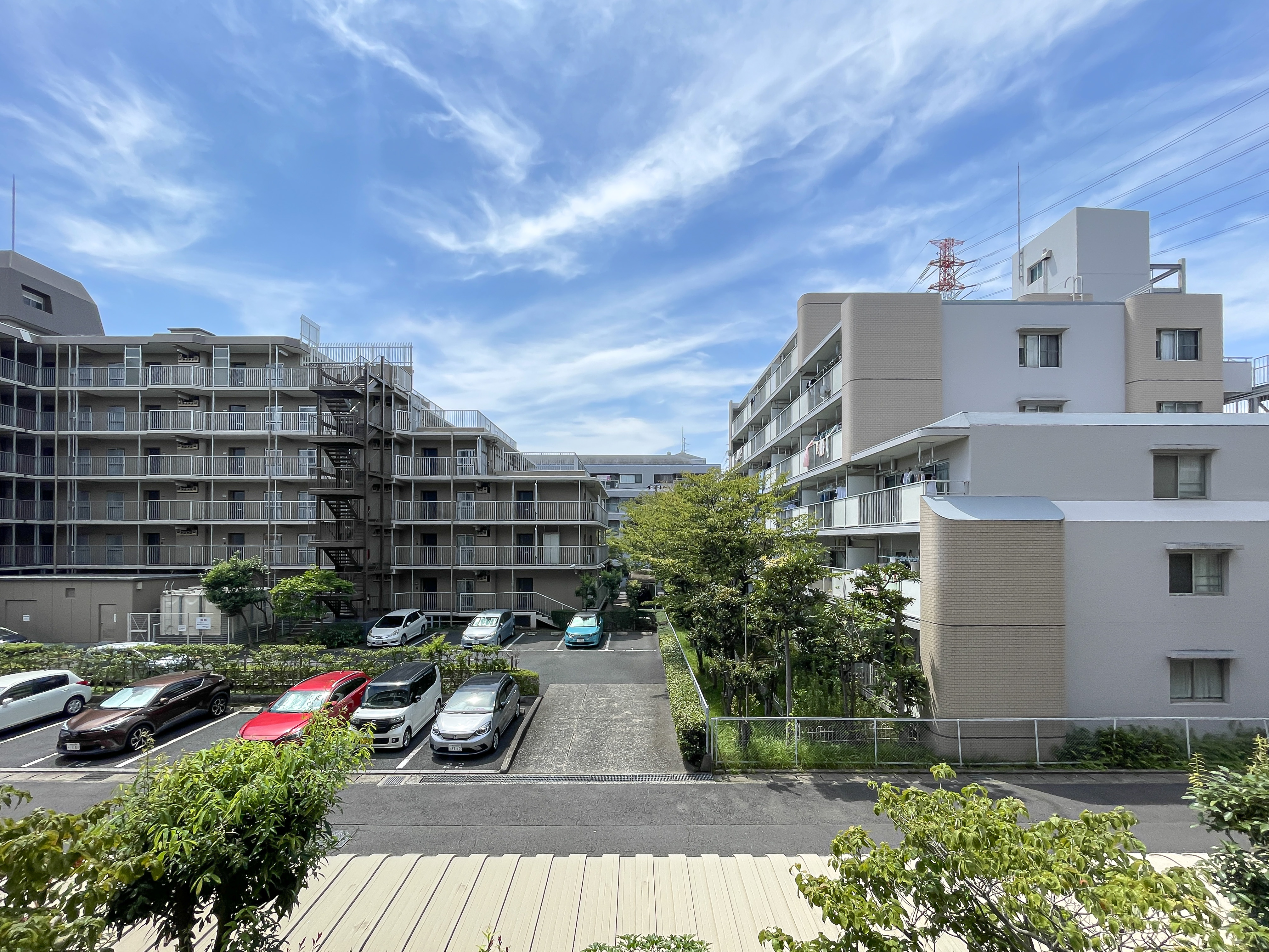 マンションの外観と周辺の駐車場・緑地を含む建物全体の様子を捉えた画像